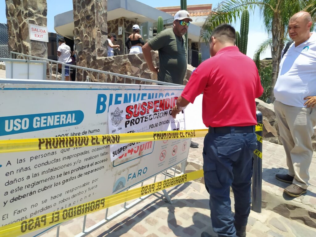 Personal de Protección Civil colocando avisos de suspensión en la entrada del Faro