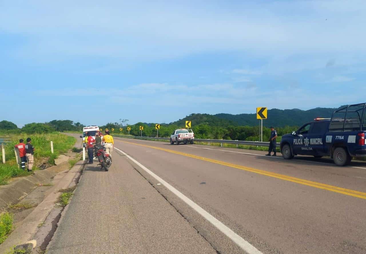 Carretera, personas y 3 camionetas, una de la policía municipal y una de la Cruz Roja