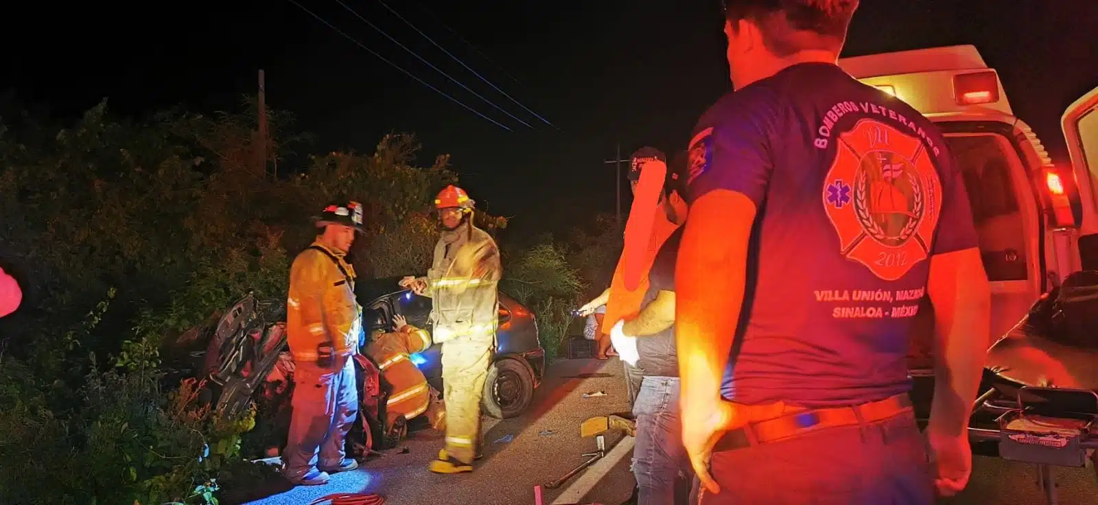 Personas con uniforme de bomberos, algunos ayudando a una persona lesionada y otras parados