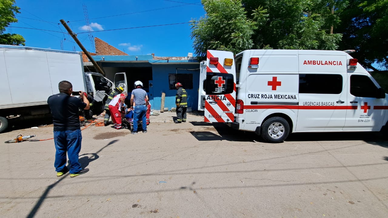 Una ambulancia de Cruz Roja con las puertas traseras abiertas, un camión chocado y personas