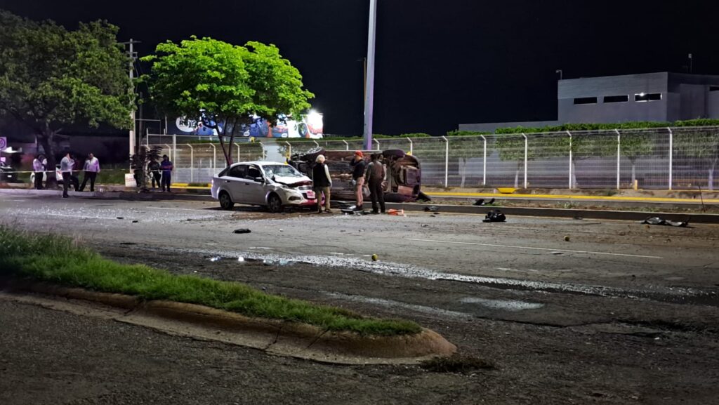 Un carro volcado y otro chocado del frente, camellón y árboles