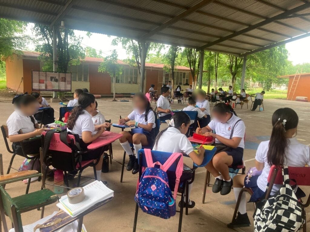 Niñas y niños estudiando bajo una techumbre