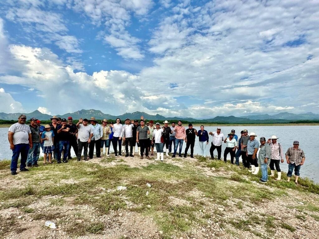 Personas reunidas y al fondo agua de una presa