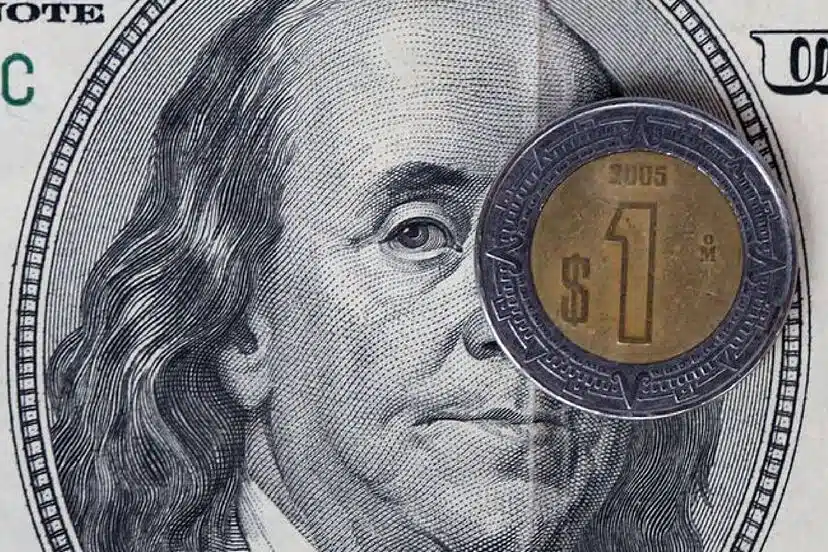 Moneda de un peso sobre billete de 100 dólares