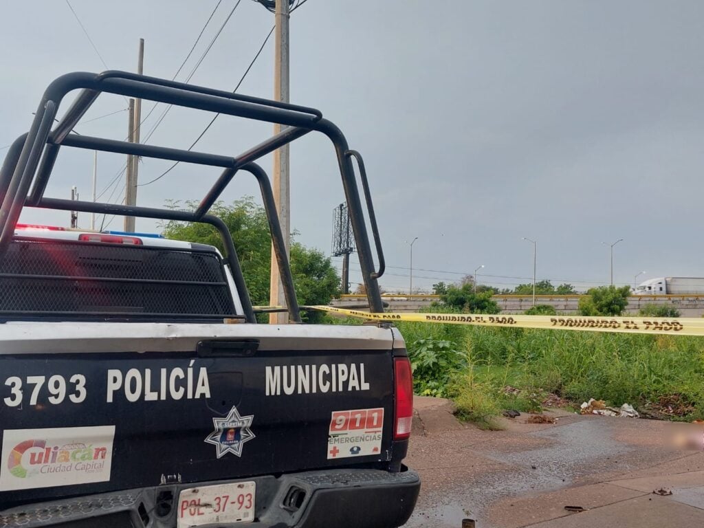 Una camioneta de la policía municipal y cinta amarilla delimitando el área de un crimen