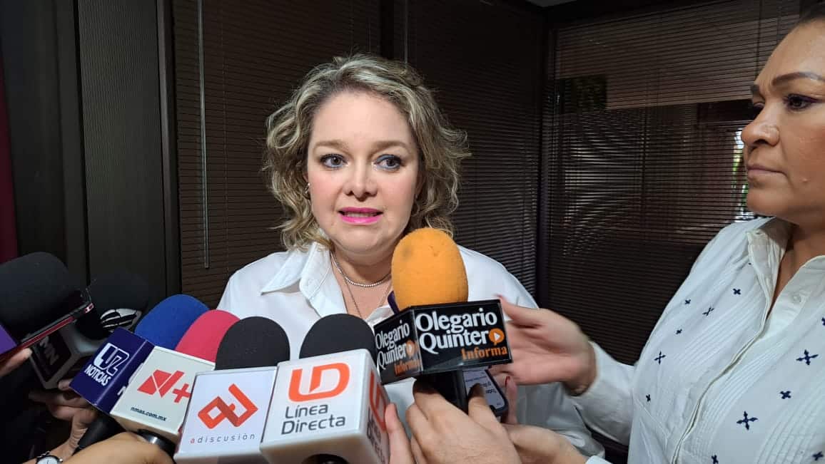 Una persona hablando y varios micrófonos de los medios de comunicación