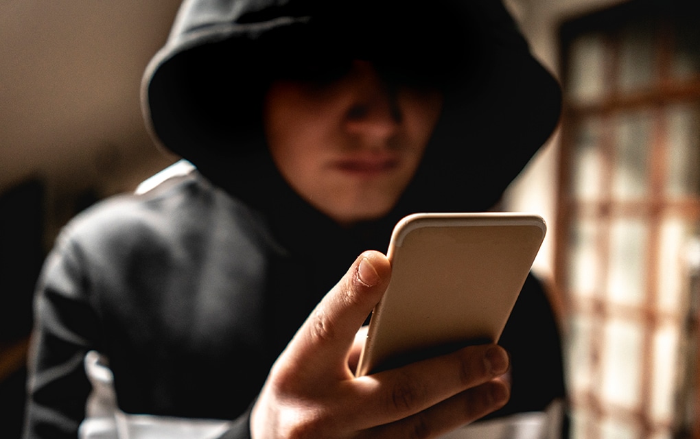 Una persona con un gorro de una sudadera y un teléfono en la mano