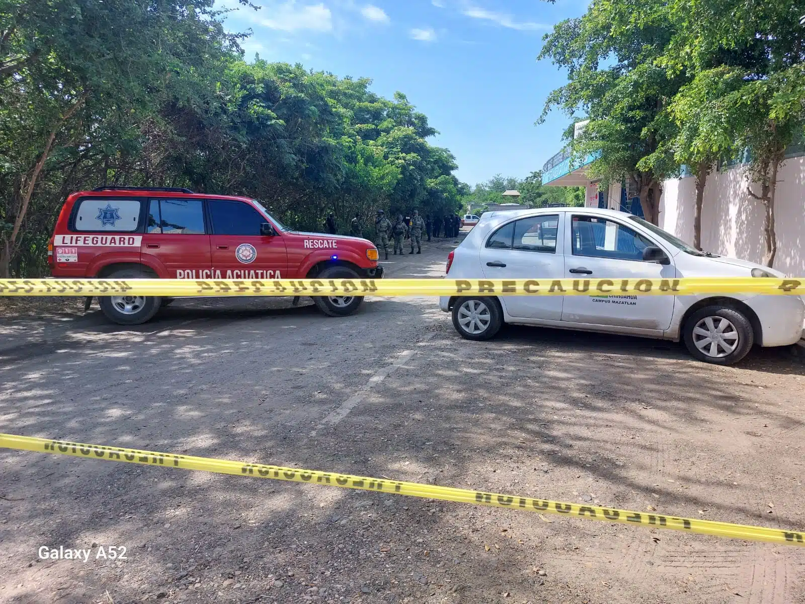 Una camioneta y un carro, cinta amarilla delimitando el área de un crimen