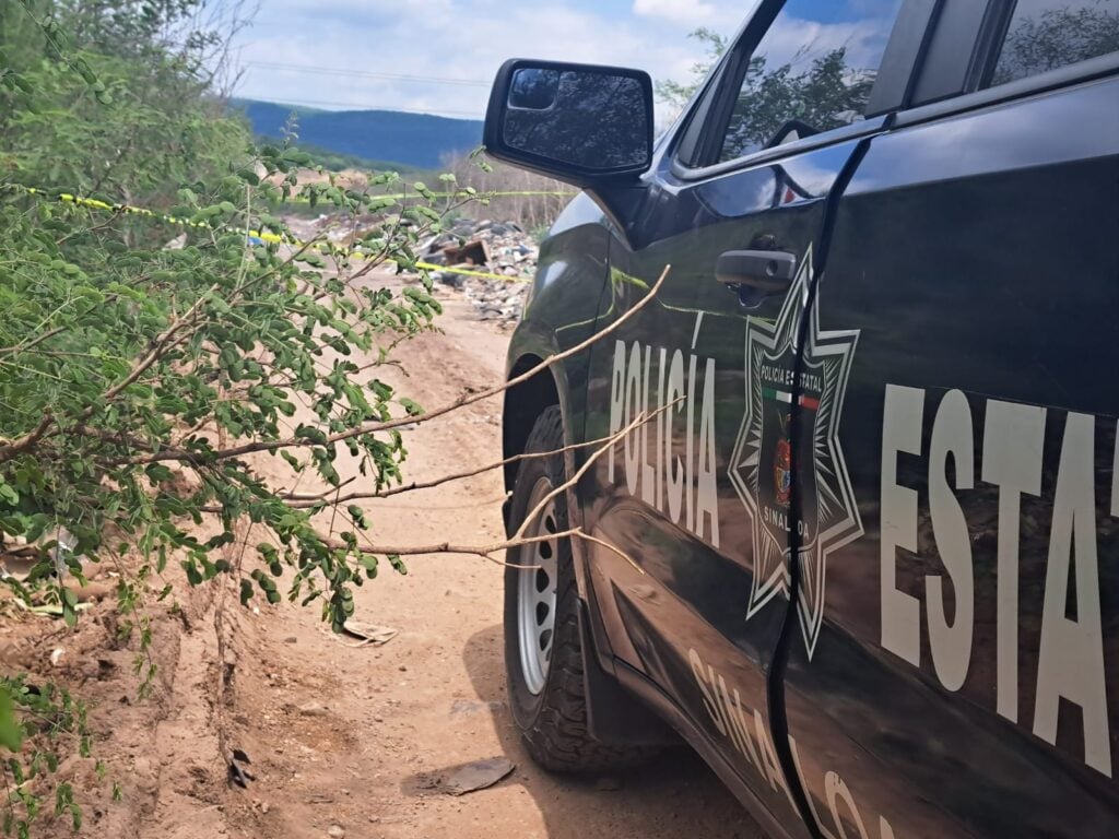 Camioneta de la Policía Municipal de Culiacán, una calle de terracería, árboles y basura