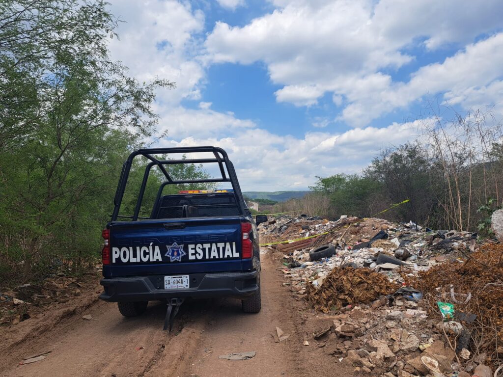 Camioneta de la Policía Municipal de Culiacán, una calle de terracería, árboles y basura
