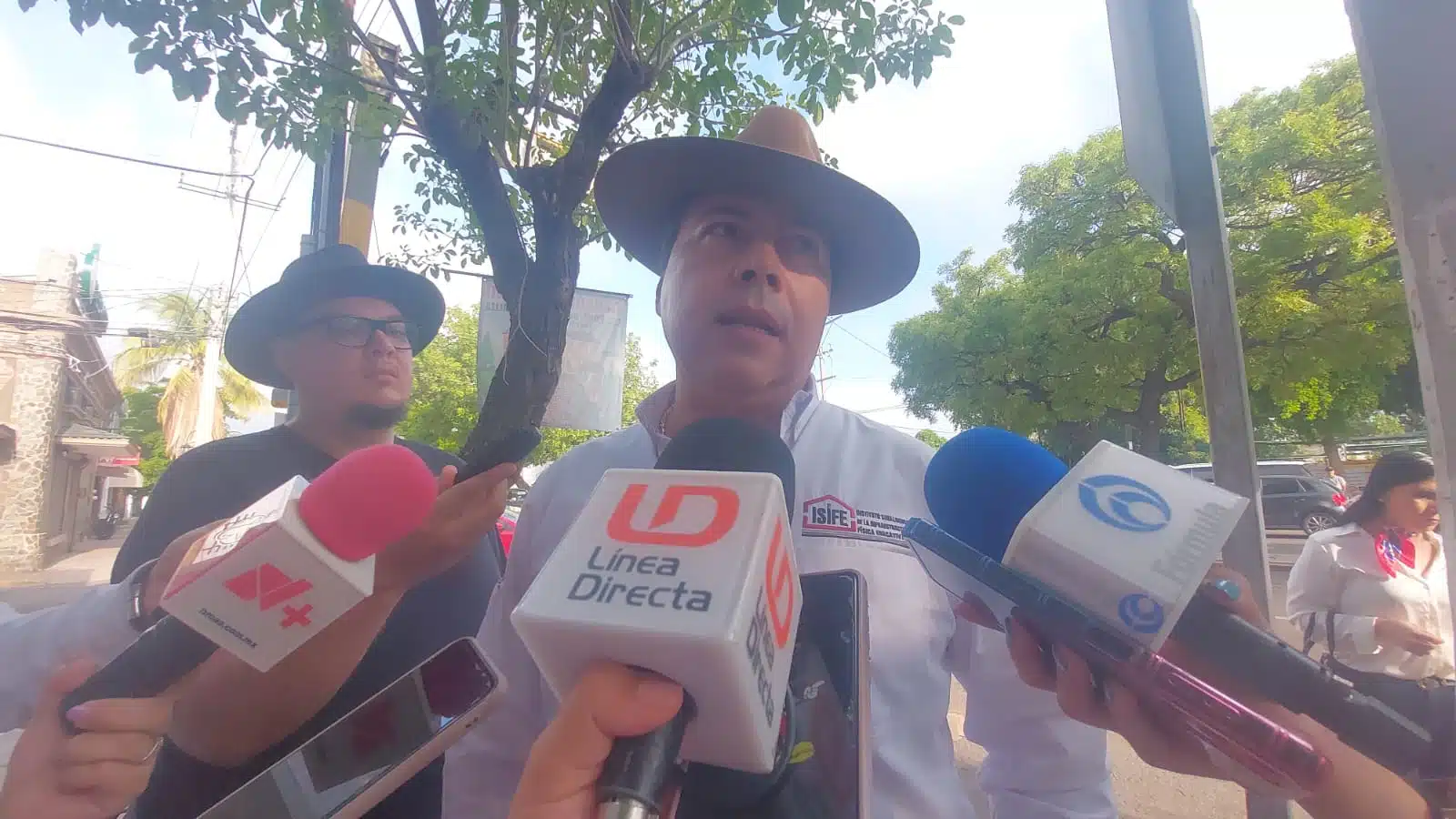 Una persona con sombrero y micrófonos de los medios de comunicación