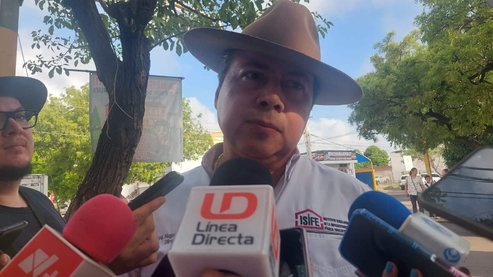 Una persona con sombrero y micrófonos de los medios de comunicación