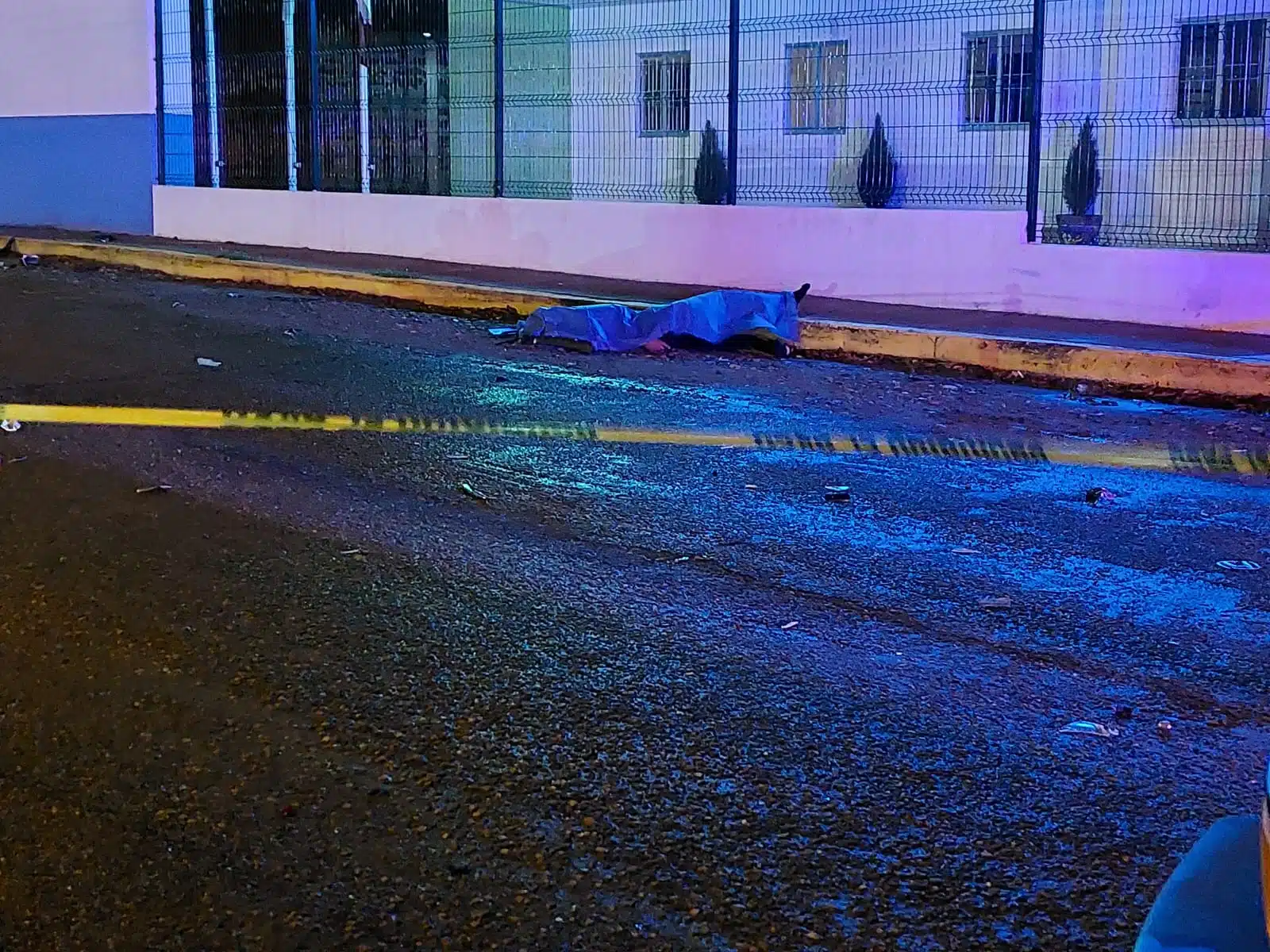 Cuerpo sin vida cubierto por sábana azul en el lugar del accidente