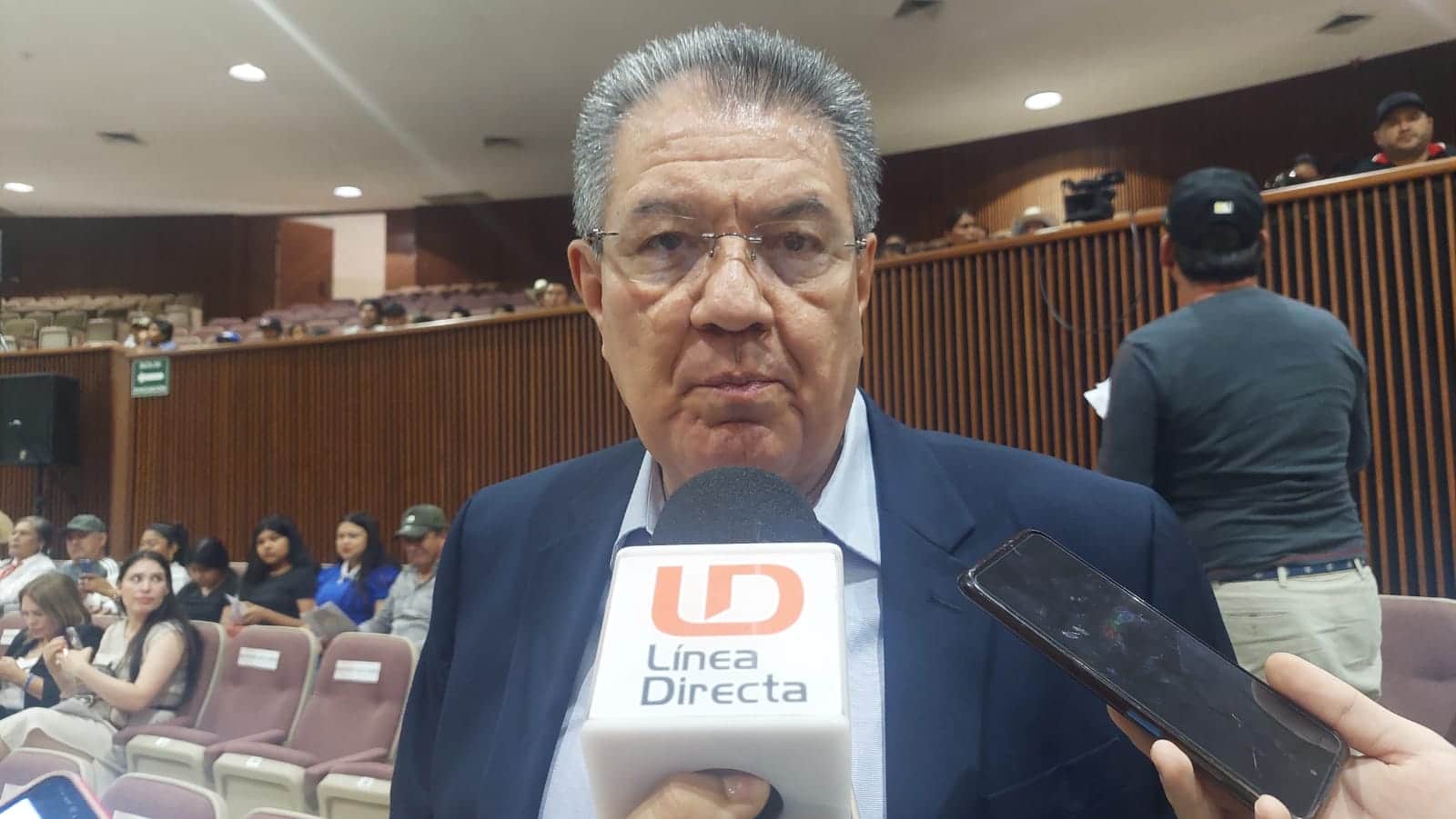 Una persona con lentes hablando y un micrófono de LD