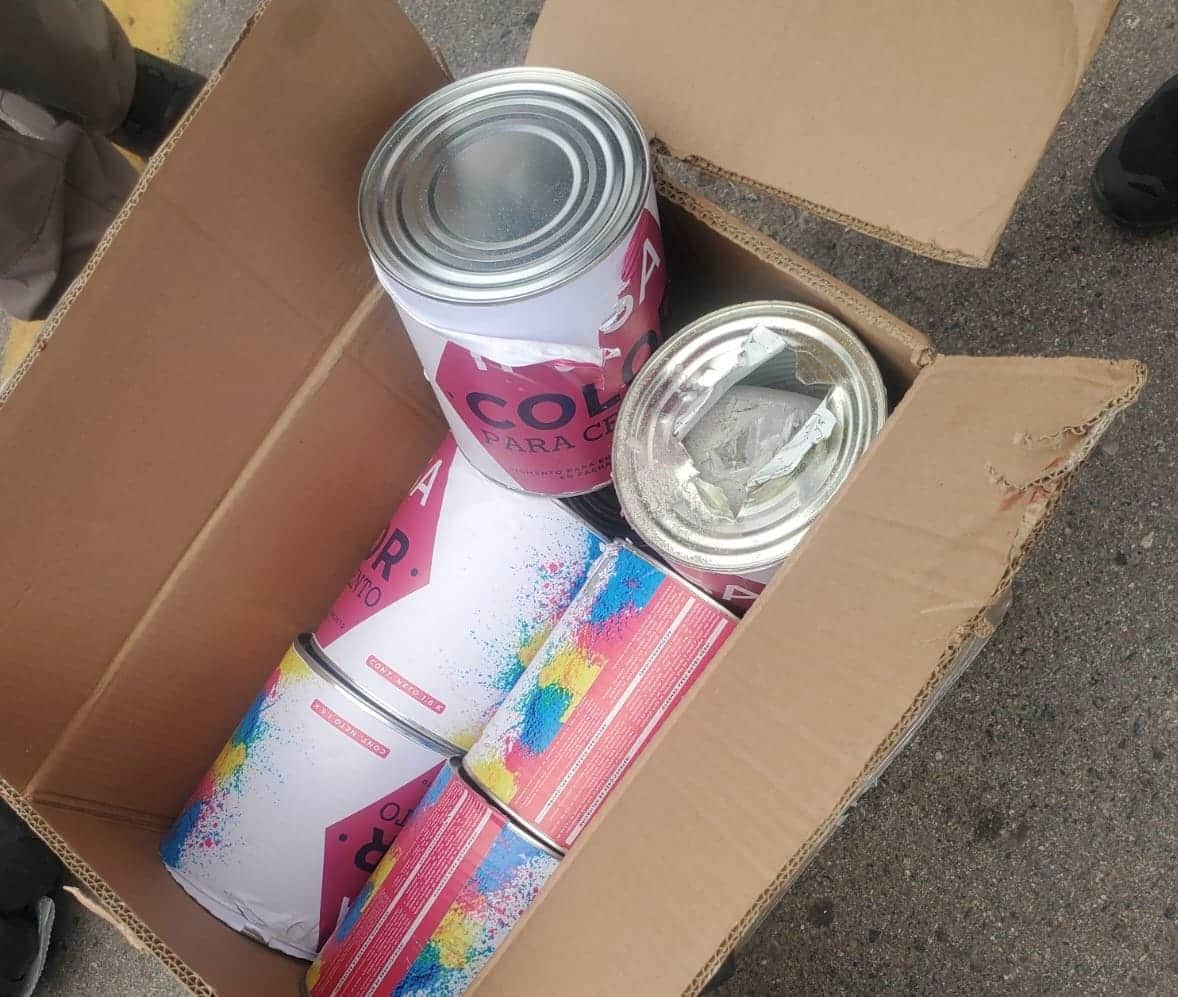 Latas de pintura abiertas en un cartón, adentro de ellas droga