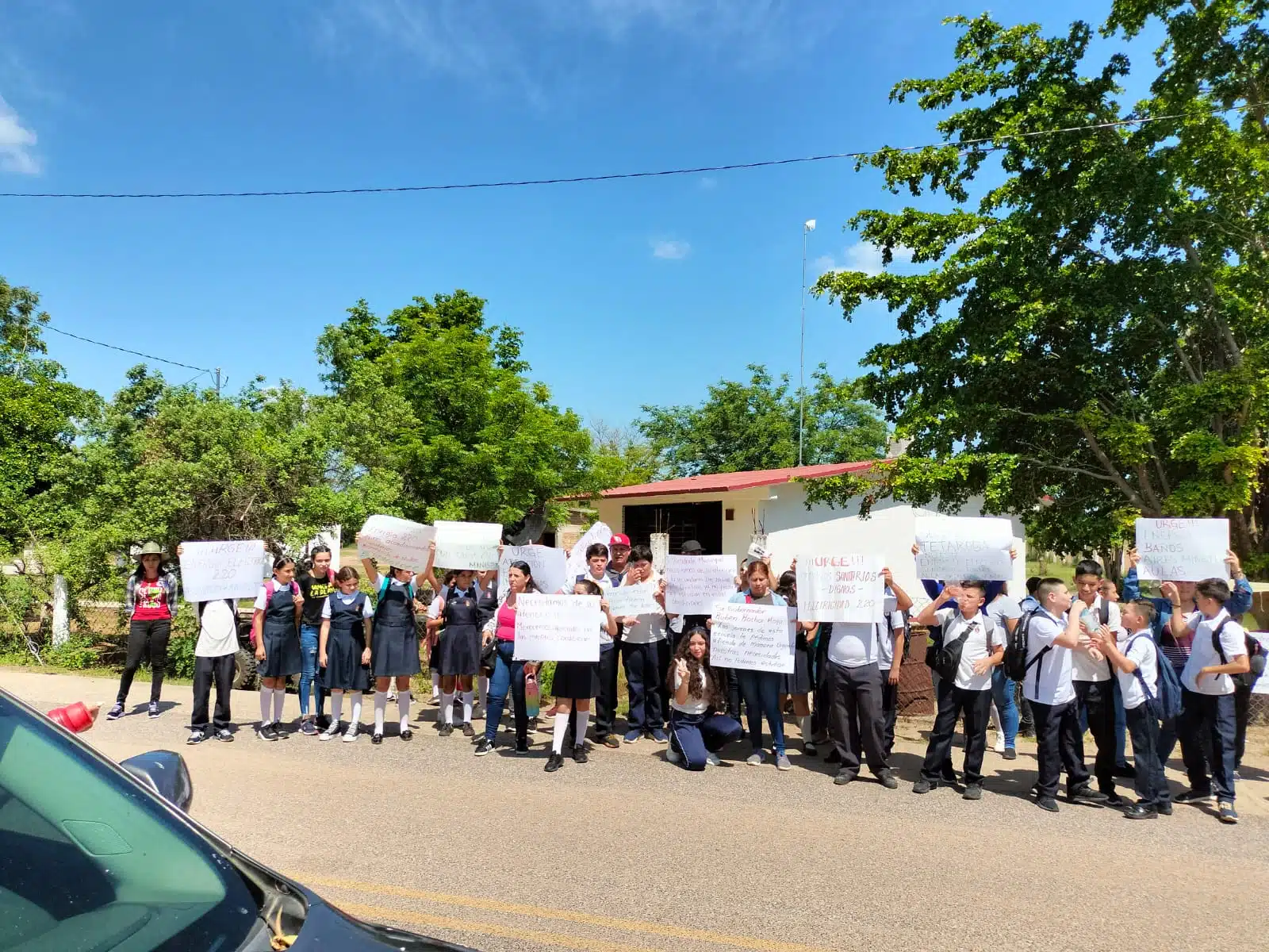 Personas con cartulinas manifestándose a un lado de la carretera