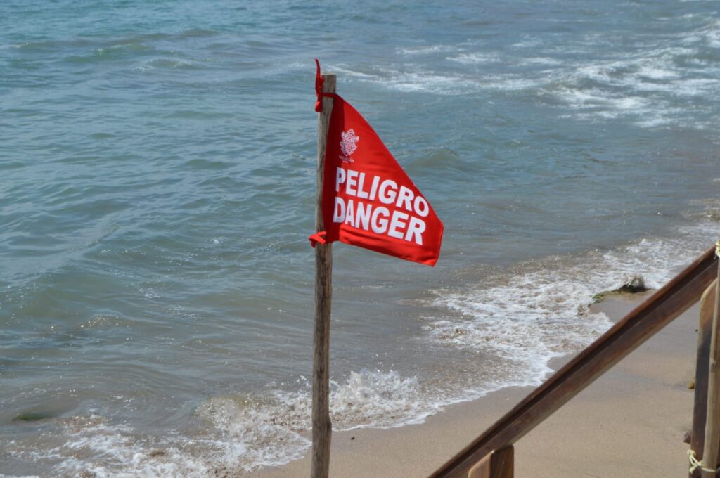 Bandera roja en la playa y agua del mar