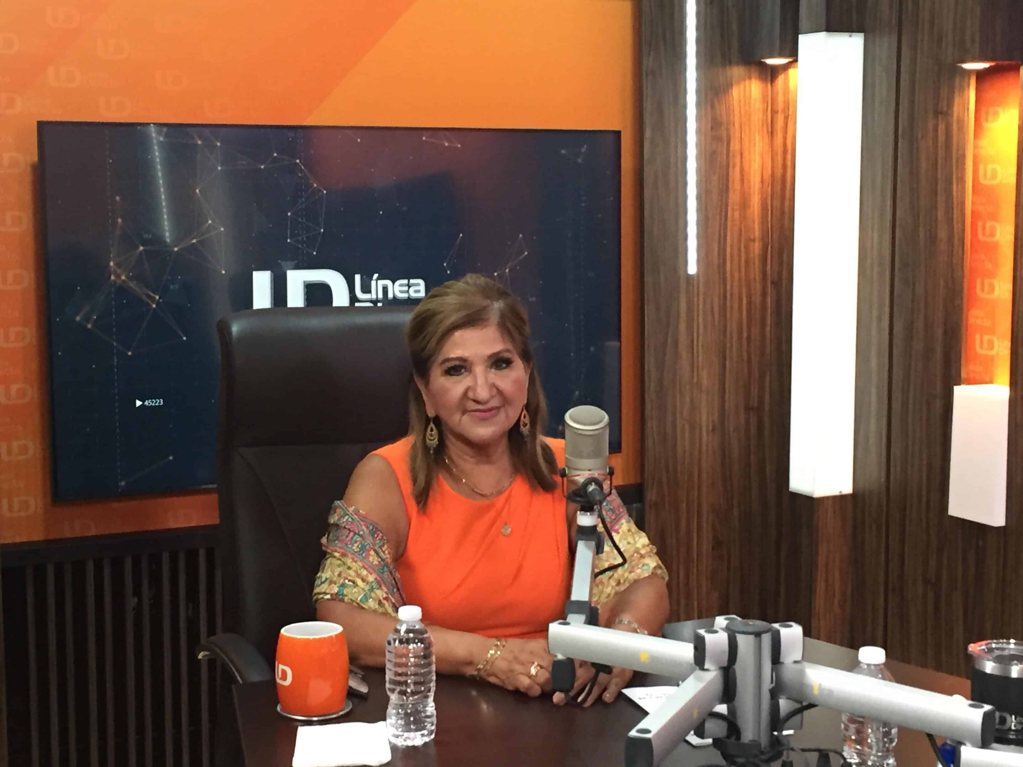 Una persona sentada y un micrófono de un medio de comunicación