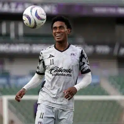 Una persona sonriendo y un balón de futbol en el aire