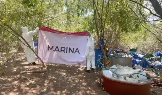 2 personas sosteniendo una manta, tambos, botes y ramas