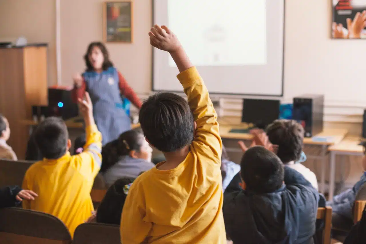 Niños levantando la mano en un aula