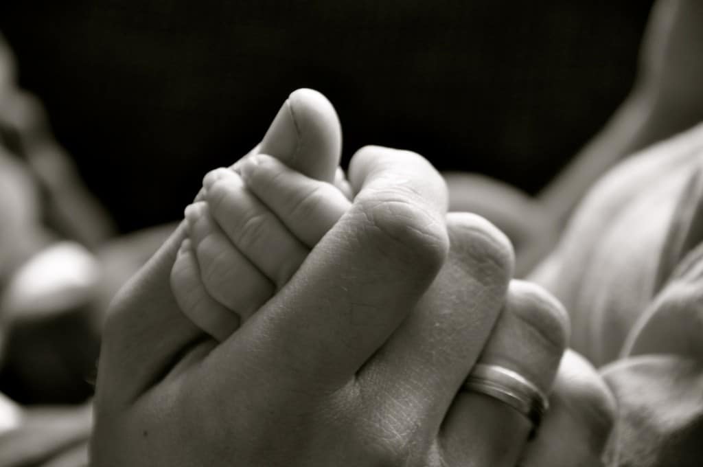Padre sosteniendo la mano de su hijo