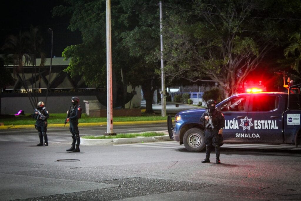 Camioneta de la Policía Estatal y personas encapuchadas paradas