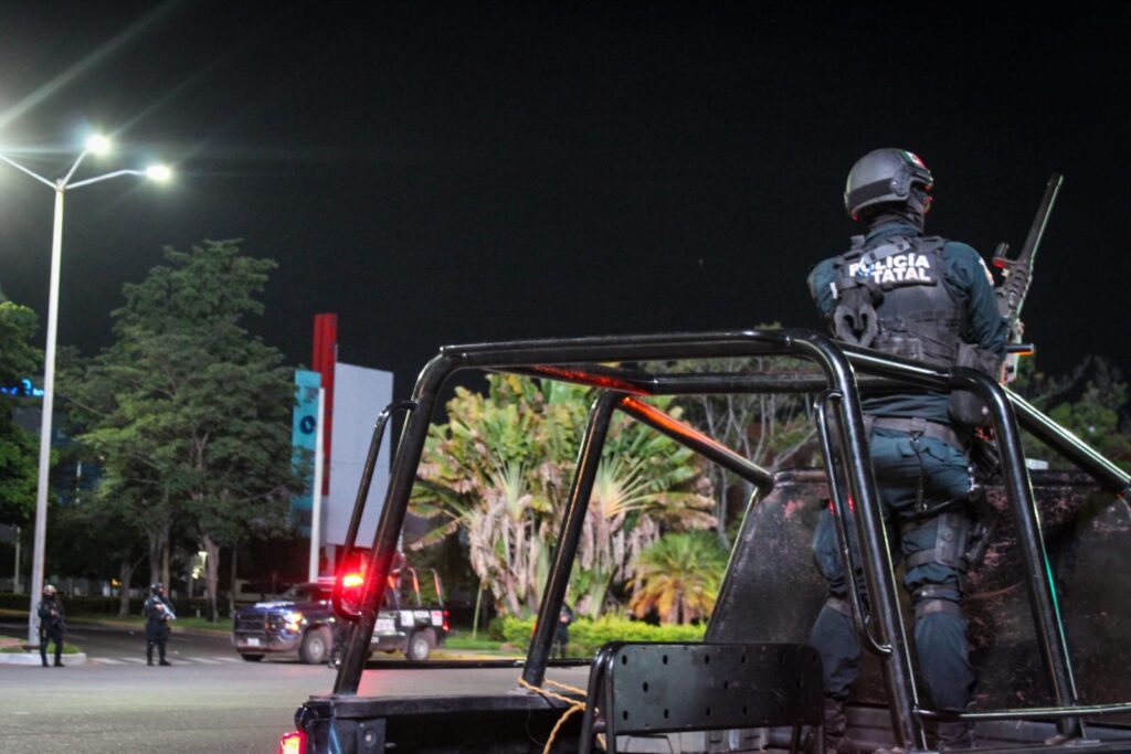 Camioneta de la Policía Estatal y una persona con uniforme de la corporación de espaldas