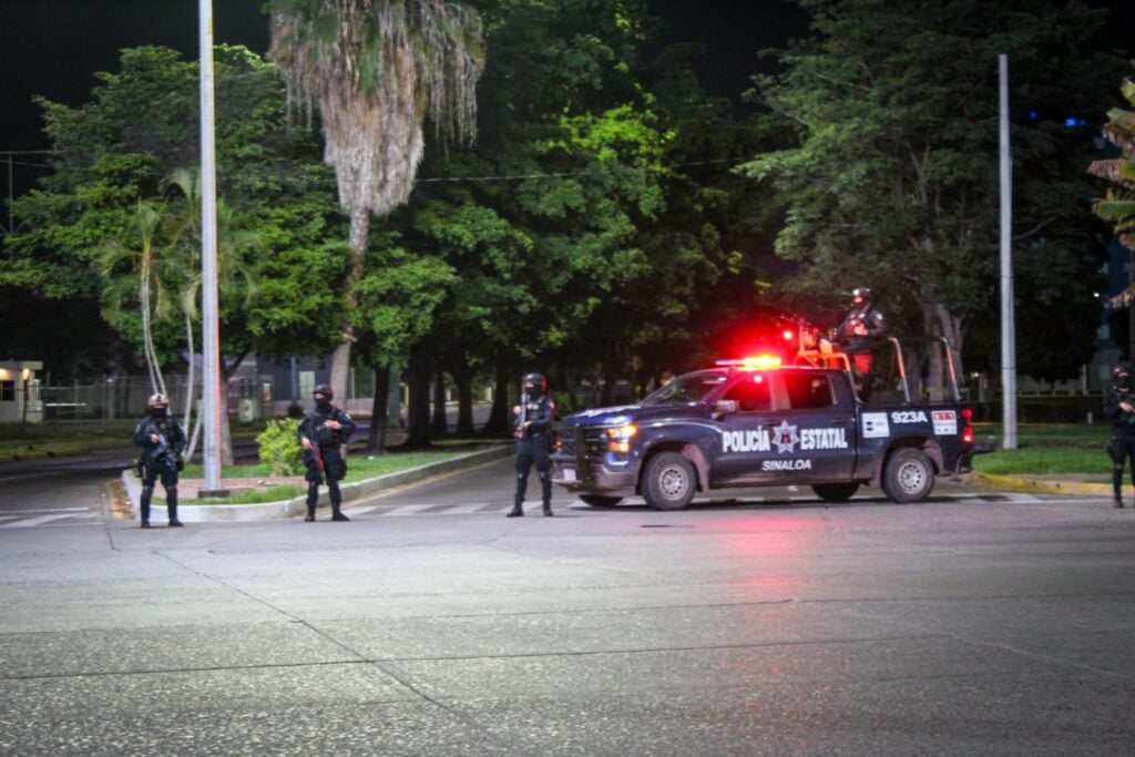 Camioneta de la Policía Estatal y personas encapuchadas paradas