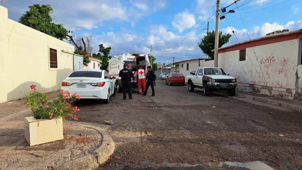 Carros estacionados, ambulancia, personas y casas