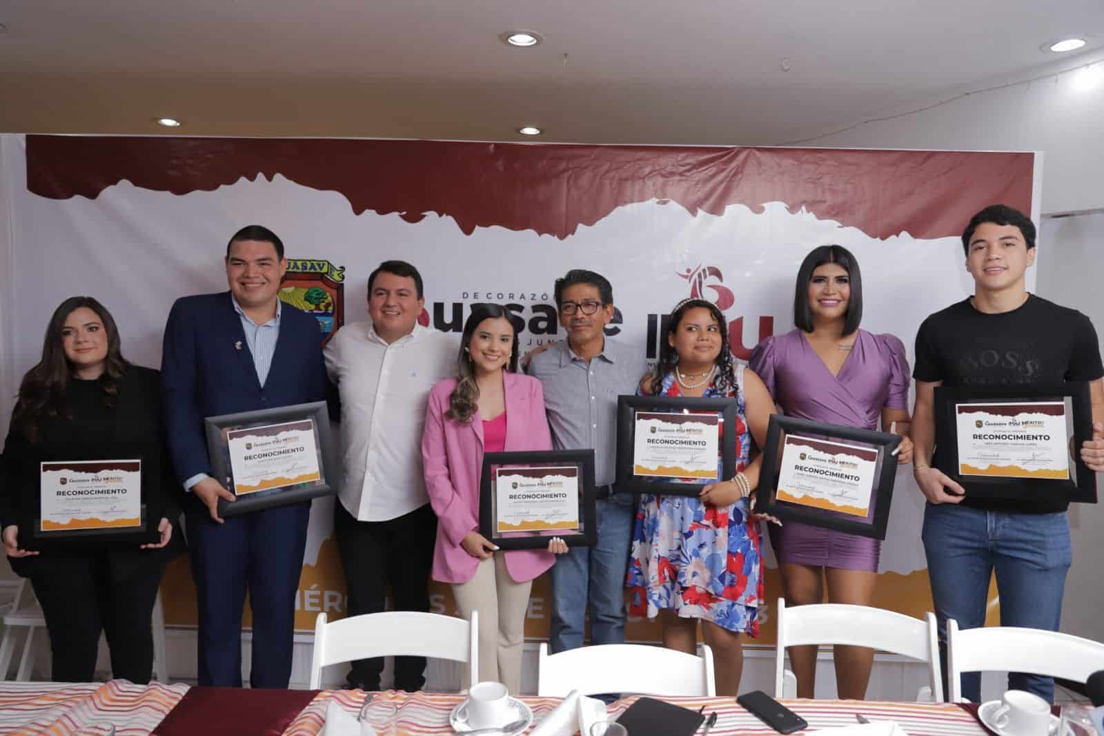 Jóvenes sosteniendo su reconocimiento con autoridades