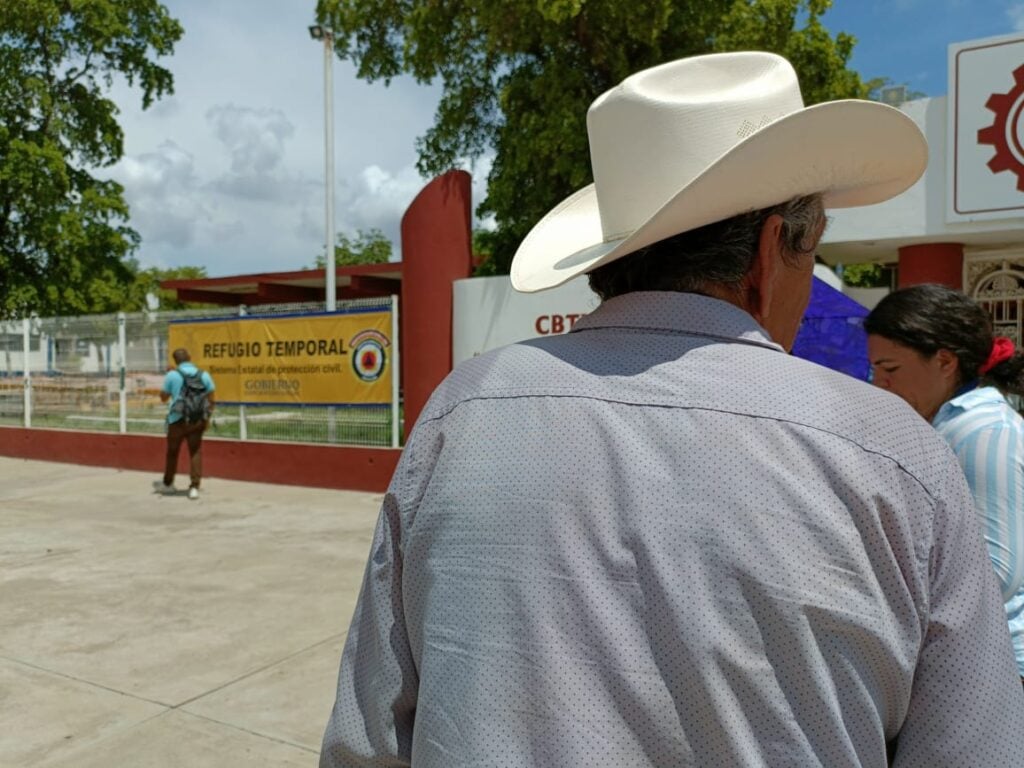 Hombre con sombrero de espaldas y frente a albergue de Guamúchil