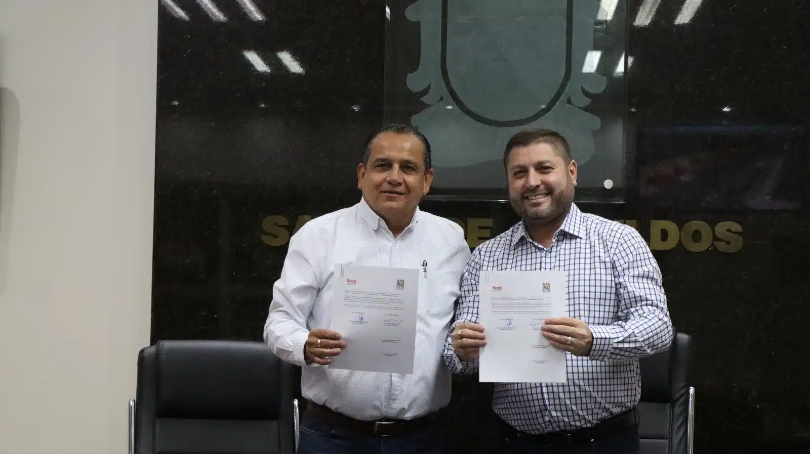 Ricardo Madrid Uriarte y José Paz López Elenes sonriendo y con documentos en las manos