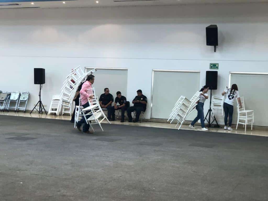 Personas cargando las sillas y otras sentadas