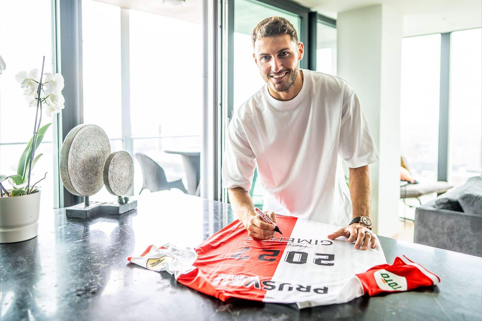 Una persona firmando una playera de futbol