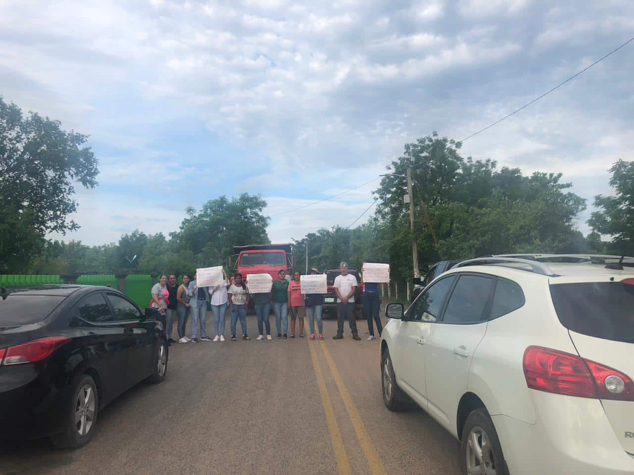 Personas con cartulinas manifestándose en la carretera y carros