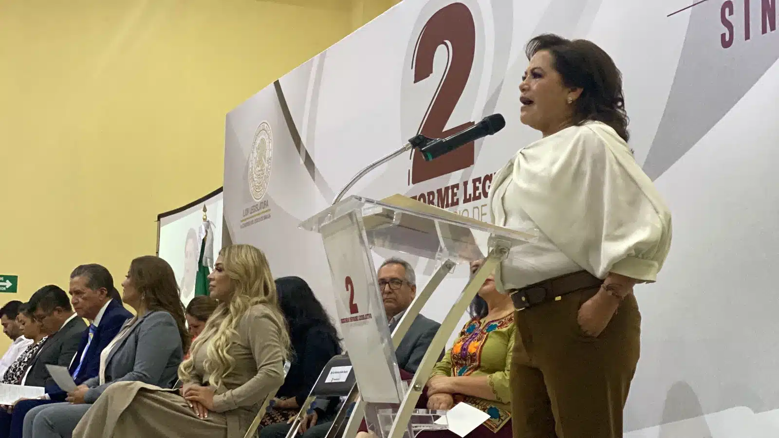 Aurelia Leal López hablando por el micrófono del podio en un evento público