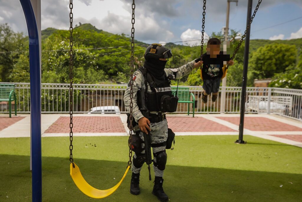 Miembro del Ejército jugando con un niño en los columpios