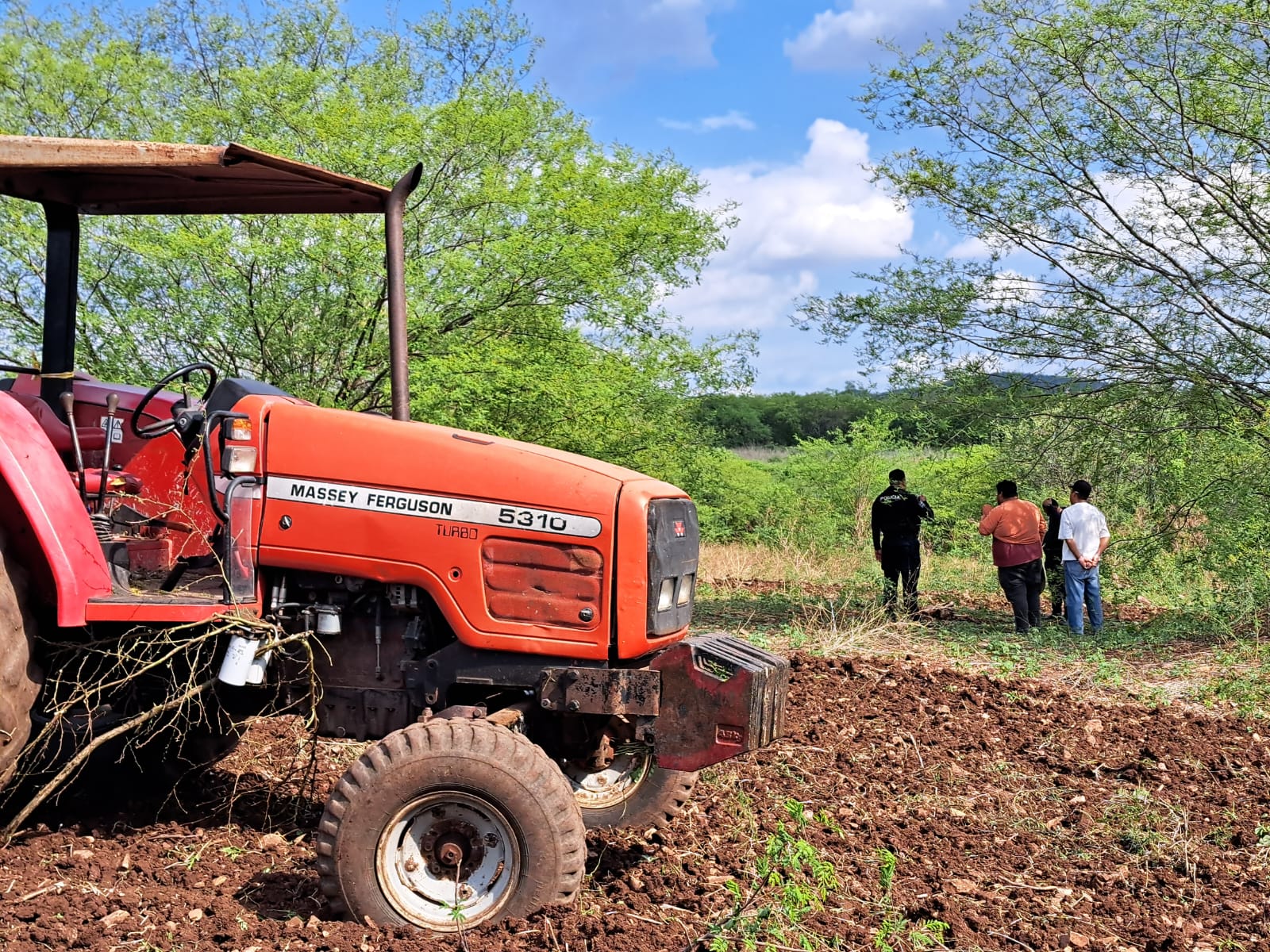 Parcelas con personas y un tractor color rojo