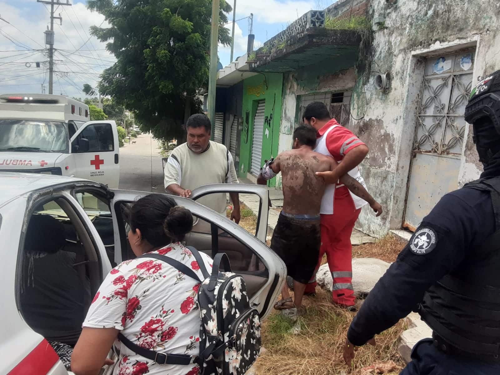 Personal de Cruz Roja camina junto con un hombre herido. Hay testigos presentes en el lugar