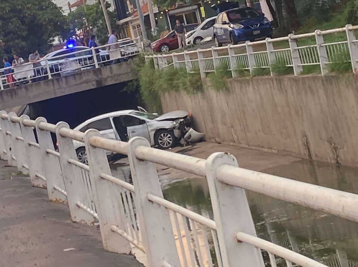 Vehículo con daños en la carrocería tras caer en canal pluvial