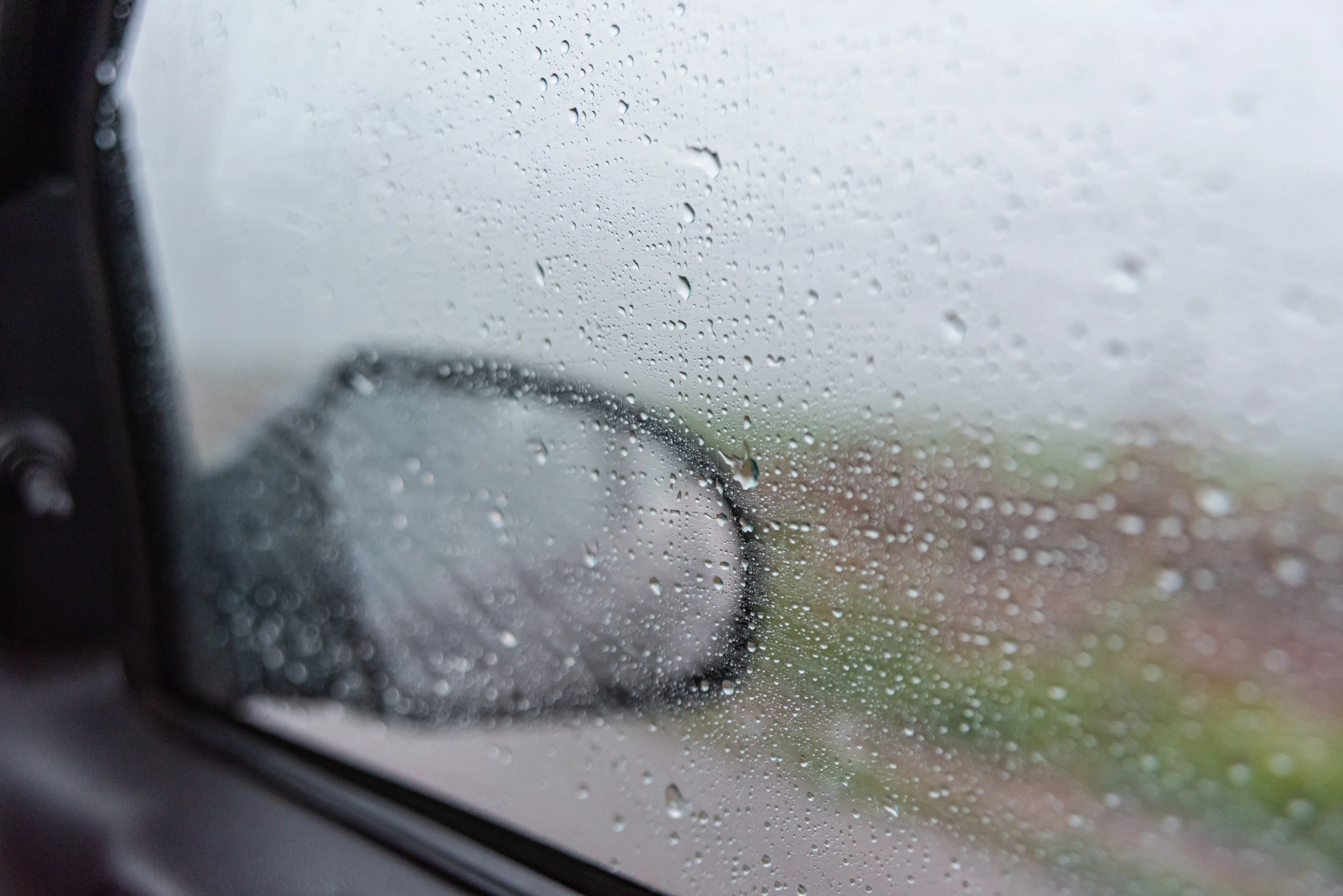 Día lluvioso detrás de ventana de automóvil en marcha