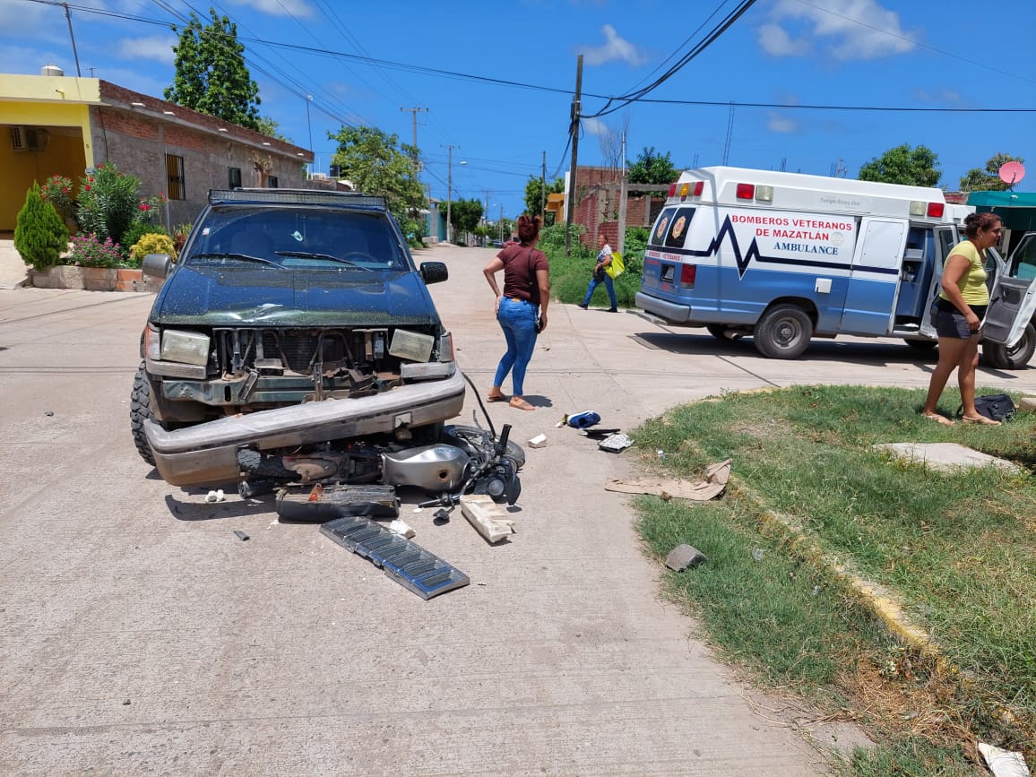 Motocicleta debajo de la parte delantera destrozada de una camioneta