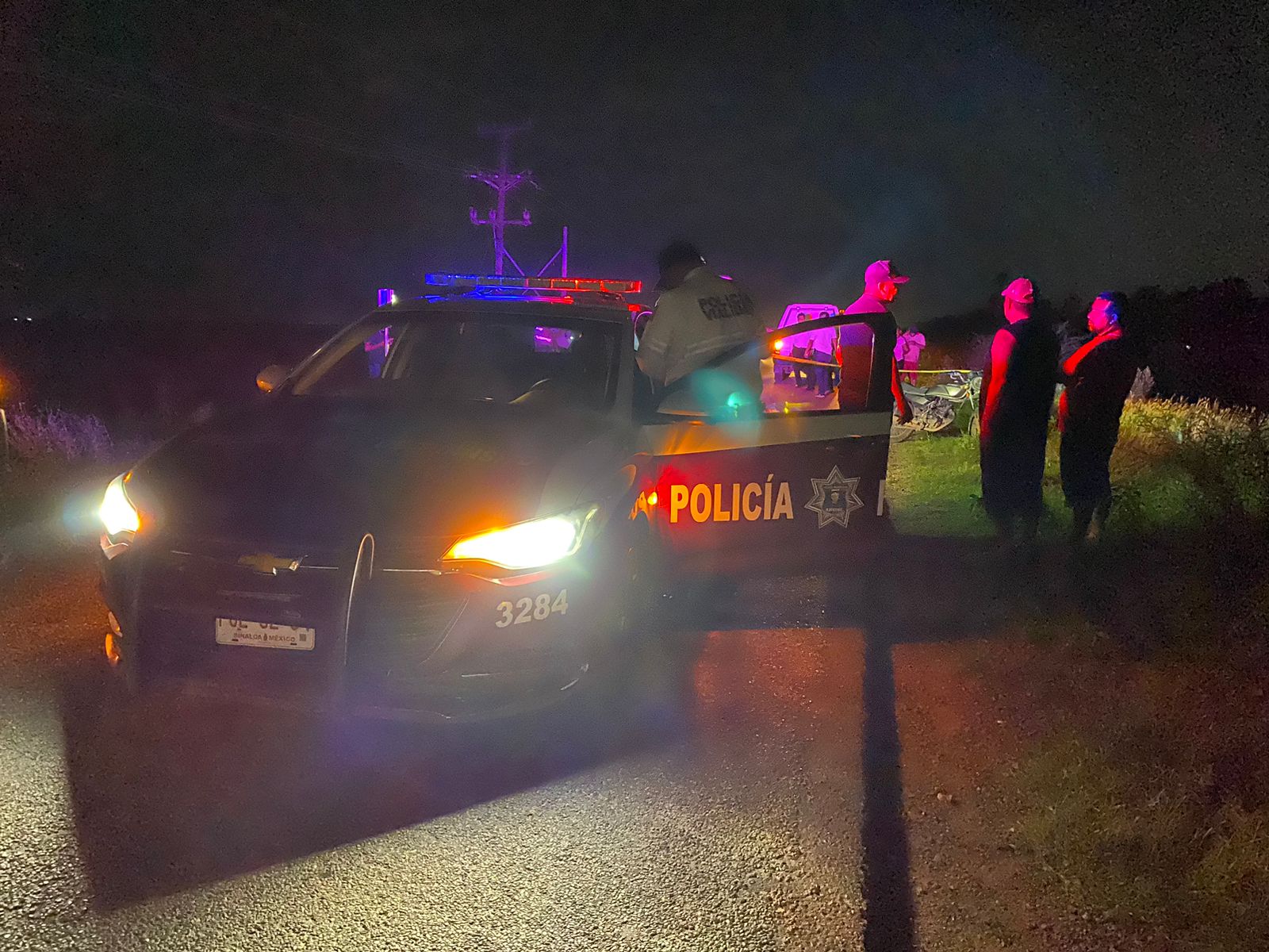 Vehículo de la Policía Municipal en el lugar de los hechos. Cerca de la zona acordonada se encuentran agentes y aparentes testigos