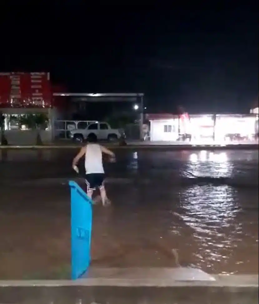 Persona intentando cruzar por una calle inundada