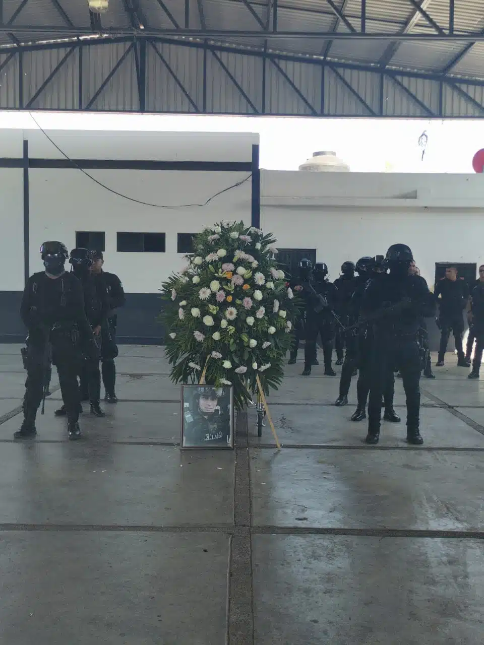 Agentes policiacos formados junto a una corona de flores y una fotografía de Irving Gabriel