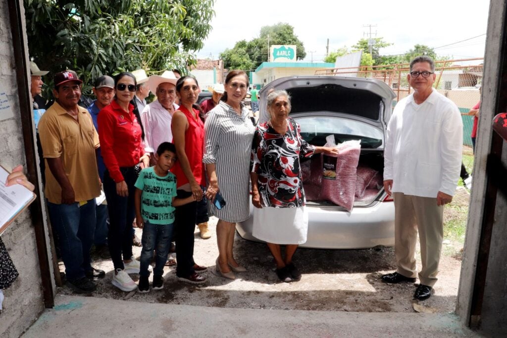 Productores junto a costales de semillas que están en la cajuela de un carro