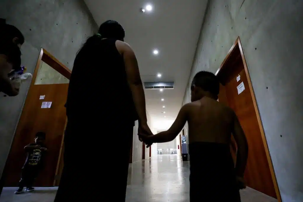 Familia migrante tomada de la mano al interior del Centro de Asistencia Social para Migrantes de DIF Sinaloa