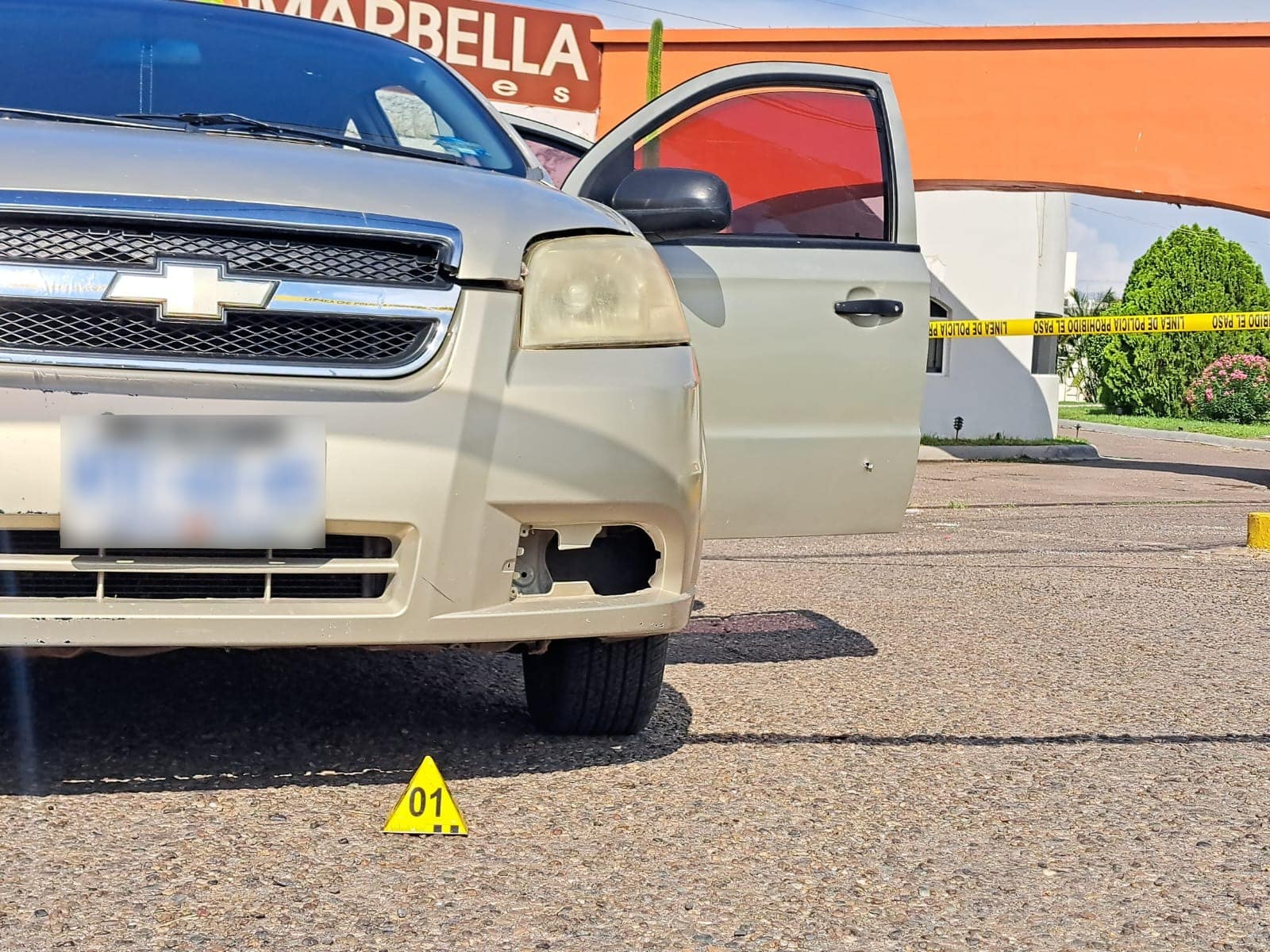 Parte delantera de un Chevrolet Aveo con un disparo en la puerta