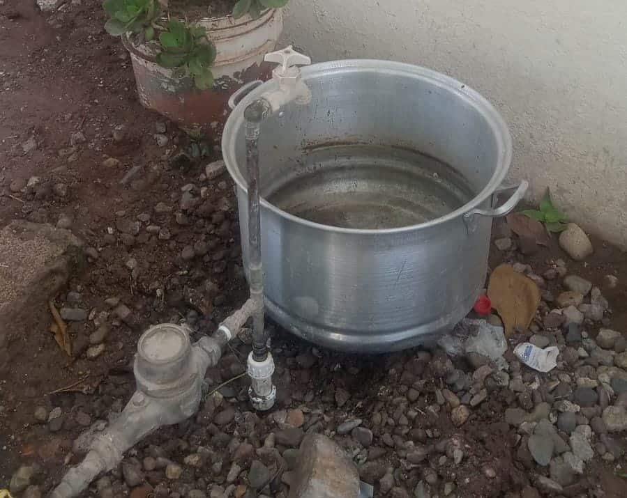 Agua de la llave cayendo sobre una olla de aluminio